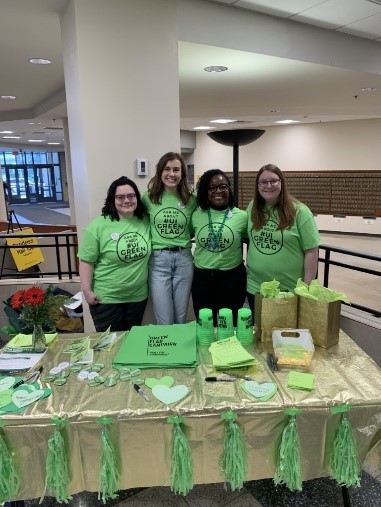 Four people at a booth wearing Green Flag Campaign shirts
